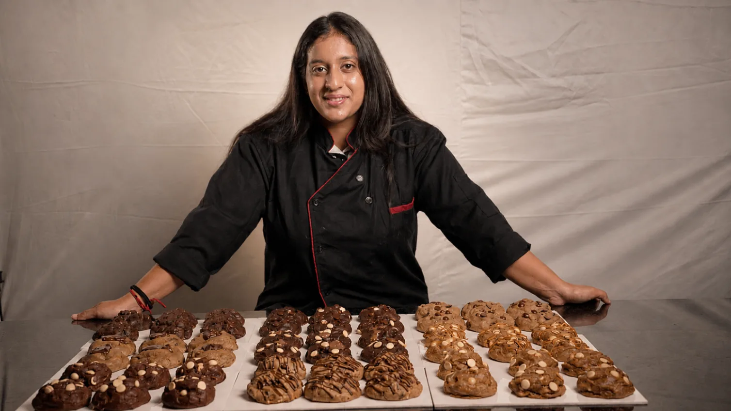 Chef Madhumitha standing behind trays of NYC cookies